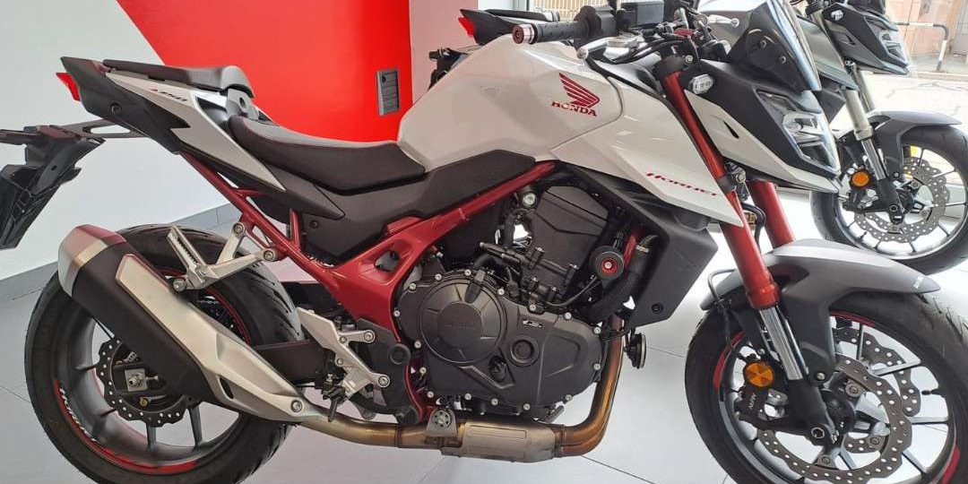 Immagine laterale moto Honda Hornet di colore bianco nel negozio Rinomotor's - Seitenansicht eines weißen Honda Hornet Motorrads im Geschäft von Rinomotor’s.