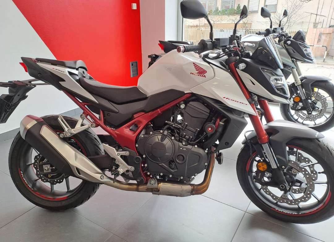 Immagine laterale moto Honda Hornet di colore bianco nel negozio Rinomotor's - Seitenansicht eines weißen Honda Hornet Motorrads im Geschäft von Rinomotor’s.