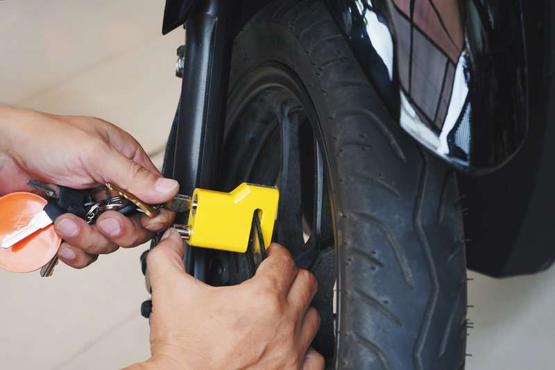 Immagine di ruota e lucchetto per moto esposto nel negozio Rinomotor's, con dettagli visibili sulla struttura e sul meccanismo di chiusura.